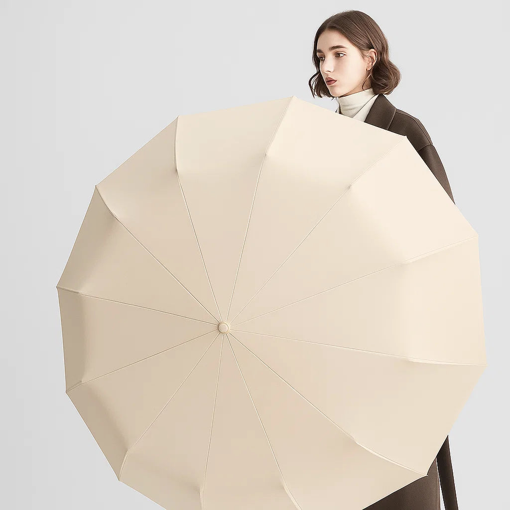 beige portable windproof umbrella held open indoors against a light background